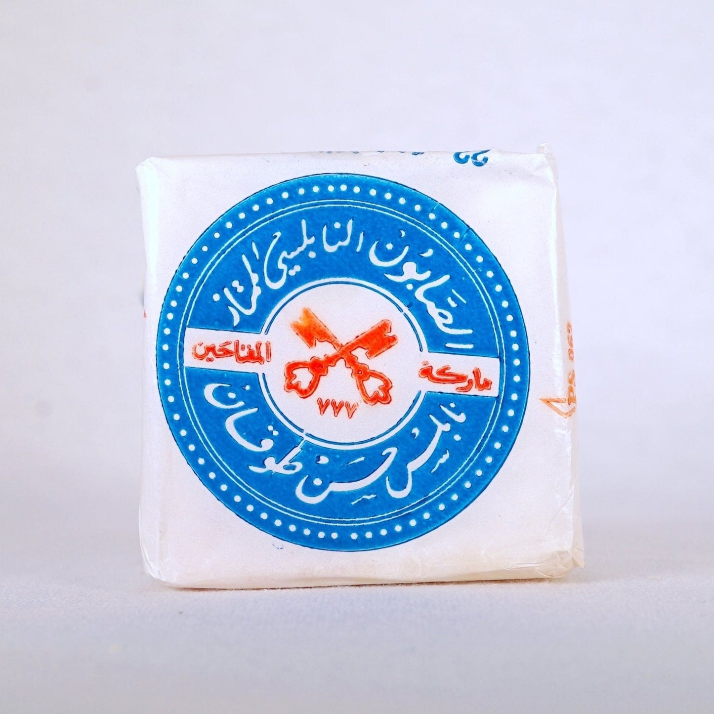 A packaged bar of soap with a blue and white label featuring text and the logo of The Two Keys imprint.