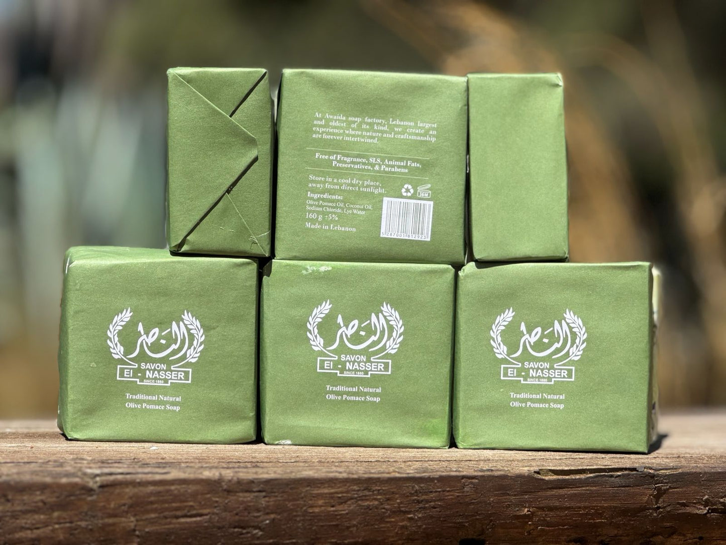 Stack of green soap boxes with branding on a wooden surface